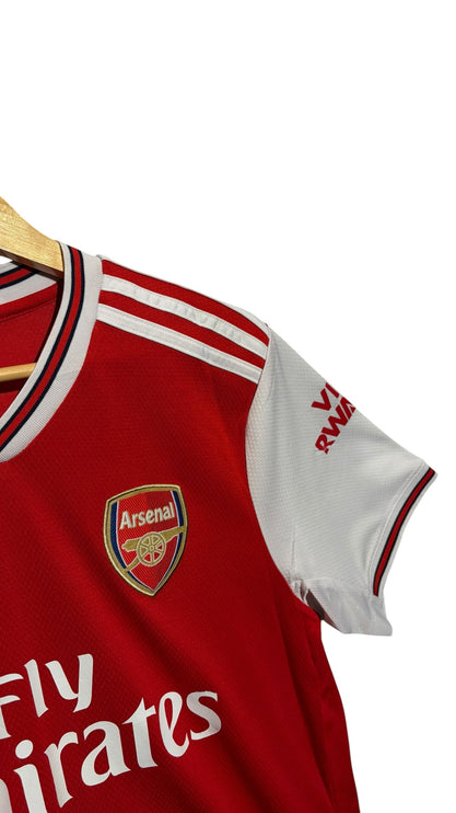OutOf10 Arsenal home football jersey featuring red body, white sleeves, club crest, and Adidas three-stripe detail.