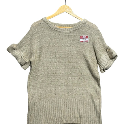 OutOf10 beige short sleeve knit sweater with crew neck, cuffed sleeves with button tabs, and ribbed hem on a hanger.