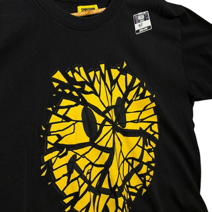 OutOf10 black cotton t-shirt featuring a yellow shattered smiley face graphic print on a wooden hanger