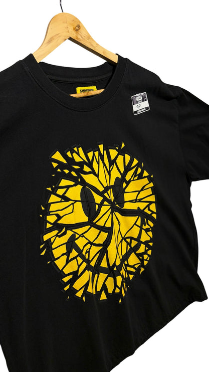 OutOf10 black cotton t-shirt featuring a yellow shattered smiley face graphic print on a wooden hanger