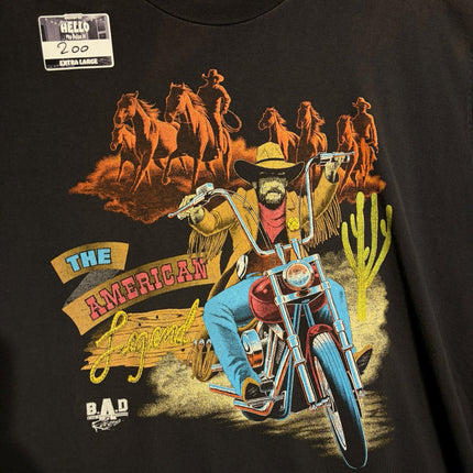 OutOf10 black cotton t-shirt featuring a vintage graphic of a cowboy riding a motorcycle with horses in the desert.