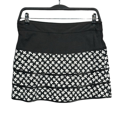 OutOf10 black and white clover print tiered athletic skirt with a wide waistband hanging on a hanger