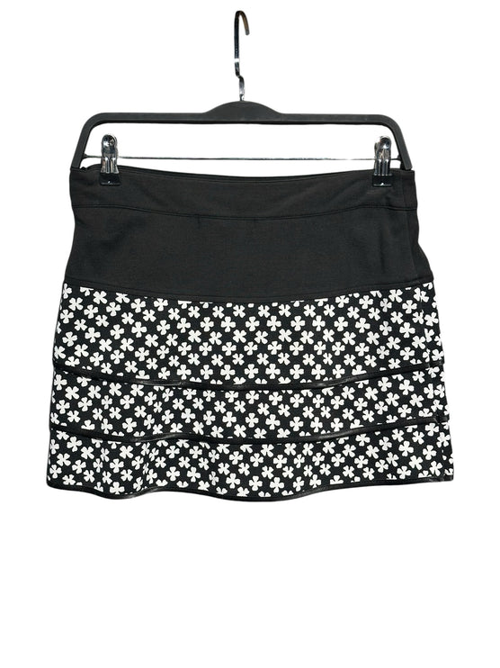 OutOf10 black and white clover print tiered athletic skirt with a wide waistband hanging on a hanger