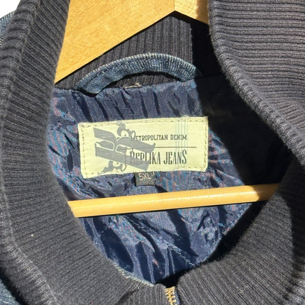 OutOf10 bomber jacket interior featuring a blue quilted lining, ribbed collar, and Metropolitan Denim brand label.