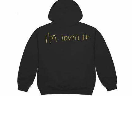 Back view of a black OutOf10 Cactus Jack x McDonald's hoodie featuring yellow hand-drawn I'm lovin it text