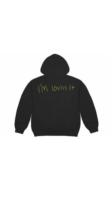 Back view of a black OutOf10 Cactus Jack x McDonald's hoodie featuring yellow hand-drawn I'm lovin it text