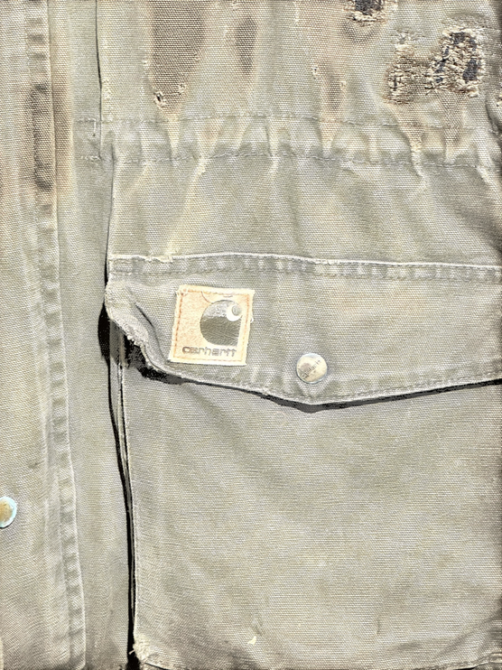 OutOf10 vintage brown Carhartt canvas field jacket with distressed texture, front pocket, and logo patch detail.