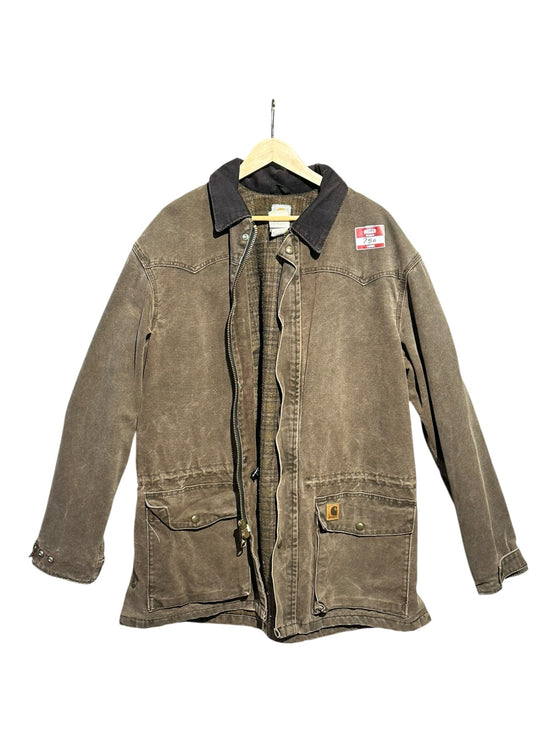 OutOf10 Carhartt brown canvas field jacket with a dark corduroy collar, front pockets, and plaid lining.