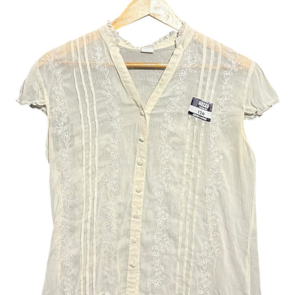 OutOf10 off-white button-down blouse with delicate floral embroidery, pintuck pleats, and ruffled cap sleeves.