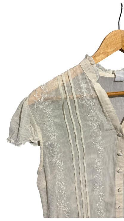 OutOf10 off-white semi-sheer blouse with floral embroidery, pintuck pleats, V-neck, and ruffled cap sleeves on hanger