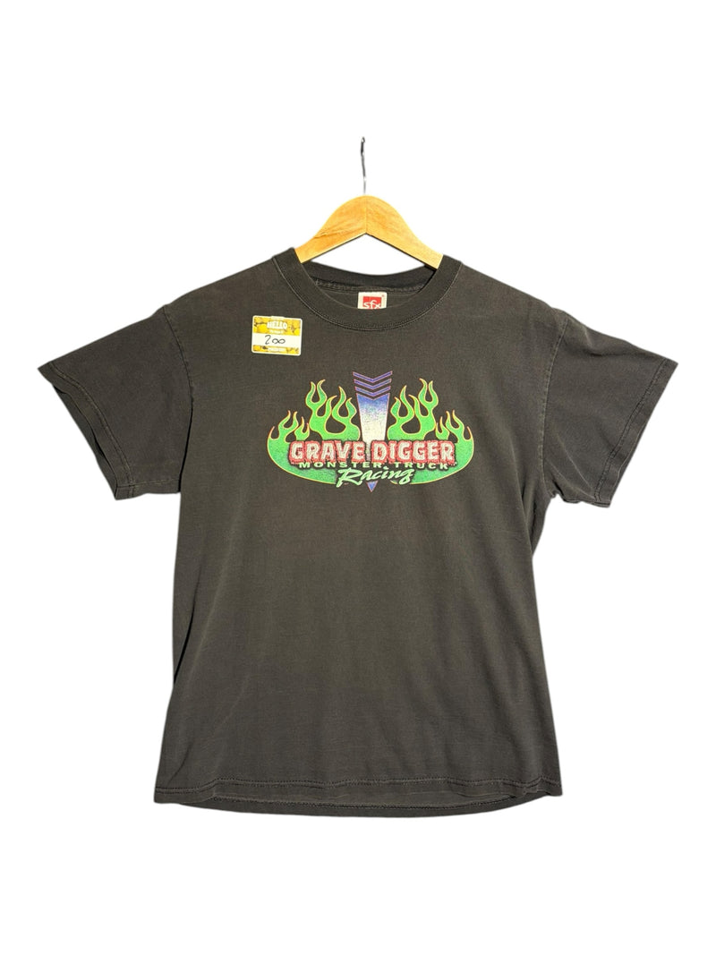 OutOf10 black cotton t-shirt featuring a Grave Digger monster truck graphic with vibrant green flames and logo.