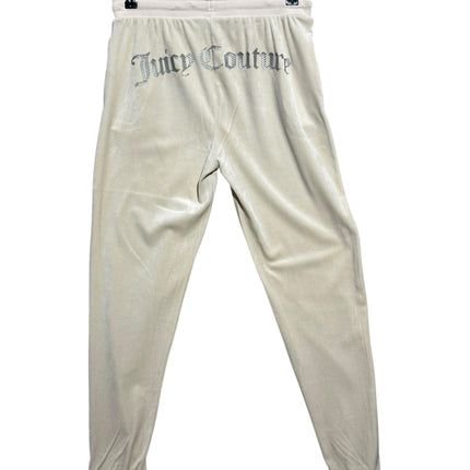 OutOf10 Juicy Couture cream velour joggers with rhinestone branding on the back, hanging on a black hanger.