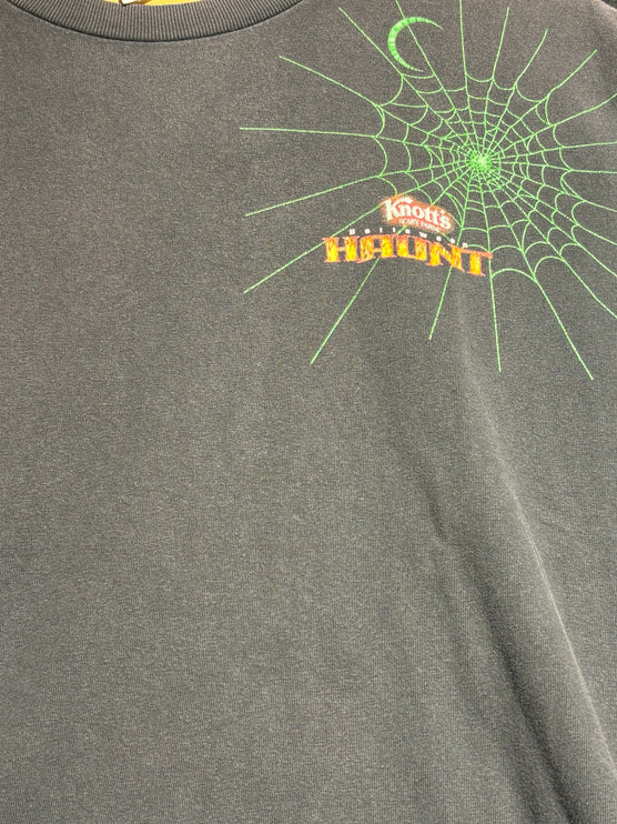OutOf10 washed-black cotton t-shirt featuring a neon-green spiderweb and Knott's Scary Farm Haunt logo on the chest.