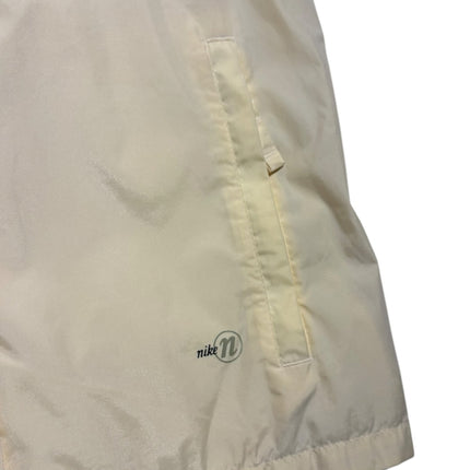 OutOf10 Nike sleeveless performance vest in cream synthetic fabric with a zippered side pocket and subtle logo detail.