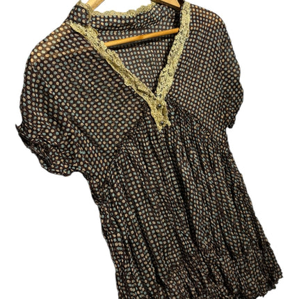 OutOf10 dark polka dot blouse with V-neckline, gold lace trim, and ruffled hem on a wooden hanger