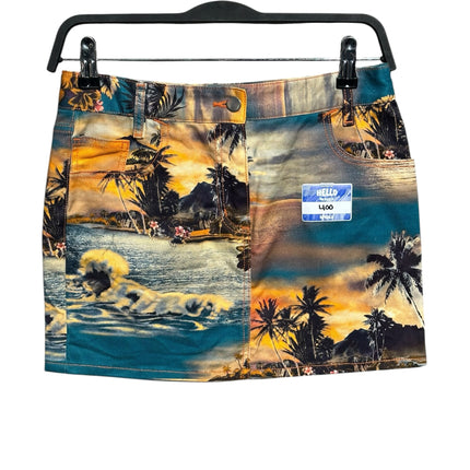 OutOf10 denim mini skirt featuring a vibrant tropical sunset landscape print with palm trees and ocean waves.